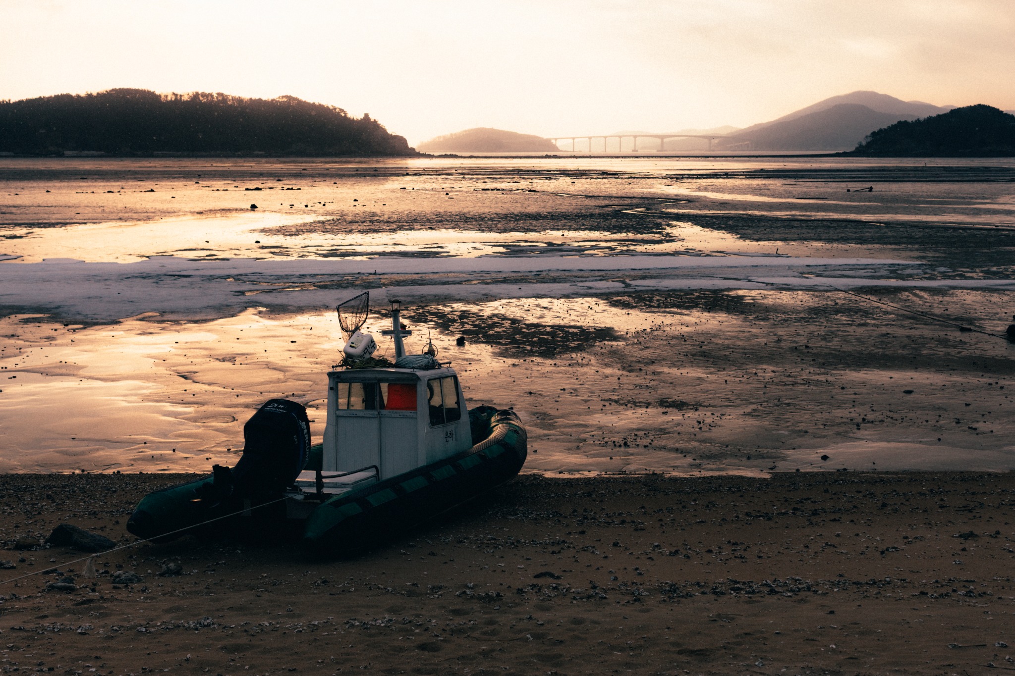A small boat resting on tidal flats at sunset